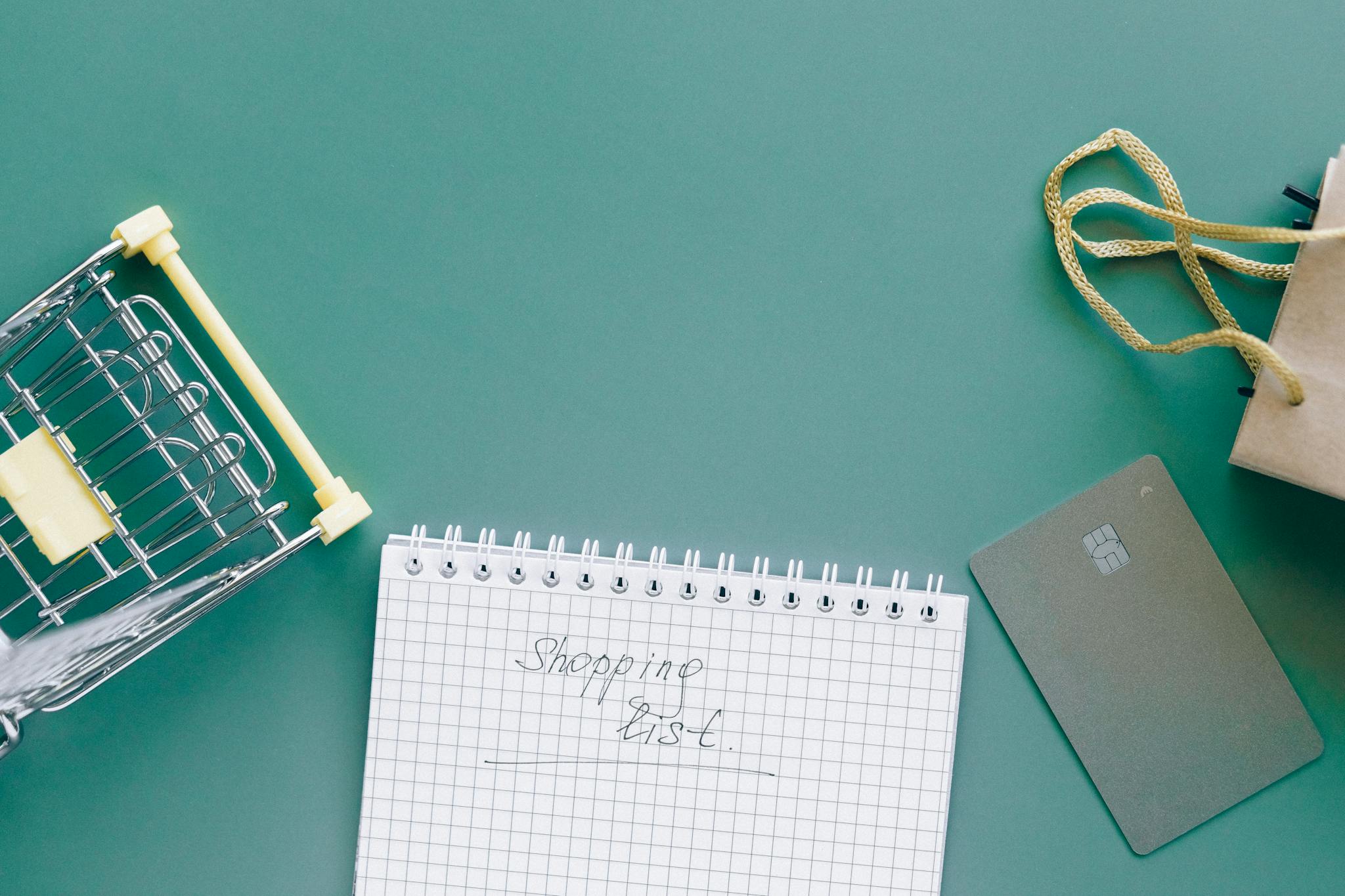 A top-down view of a shopping cart, list, card, and bag on a green background.